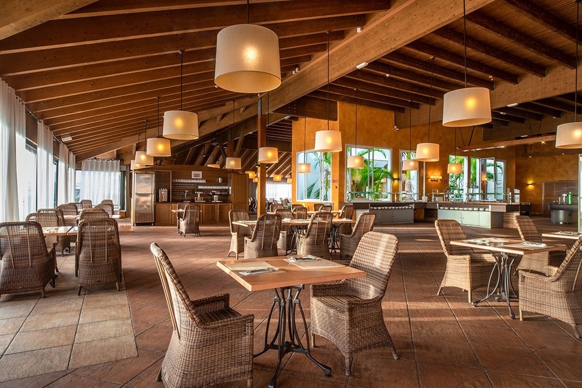 un restaurante con mesas y sillas de mimbre y techo de madera