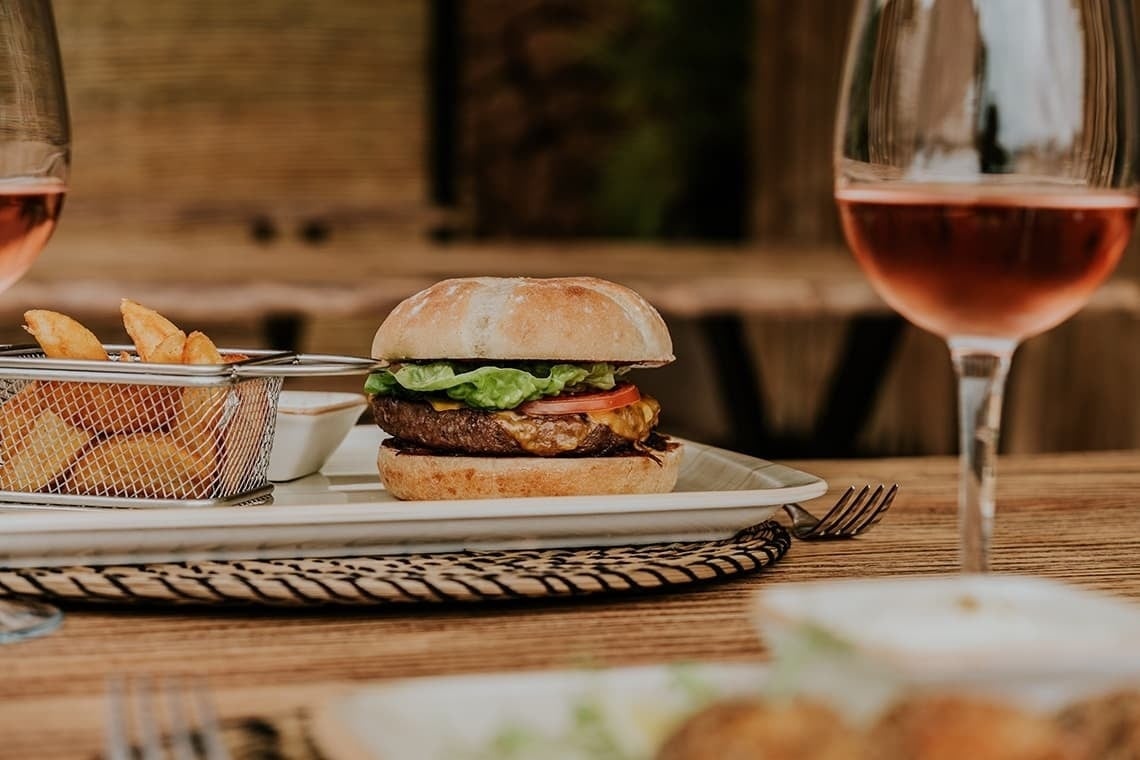 un plato de comida con una hamburguesa y papas fritas y una copa de vino