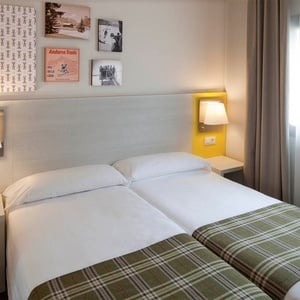 una habitación con dos camas y cuadros de andorra en la pared