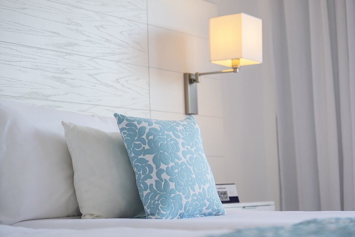 un lit avec des oreillers blancs et un oreiller bleu