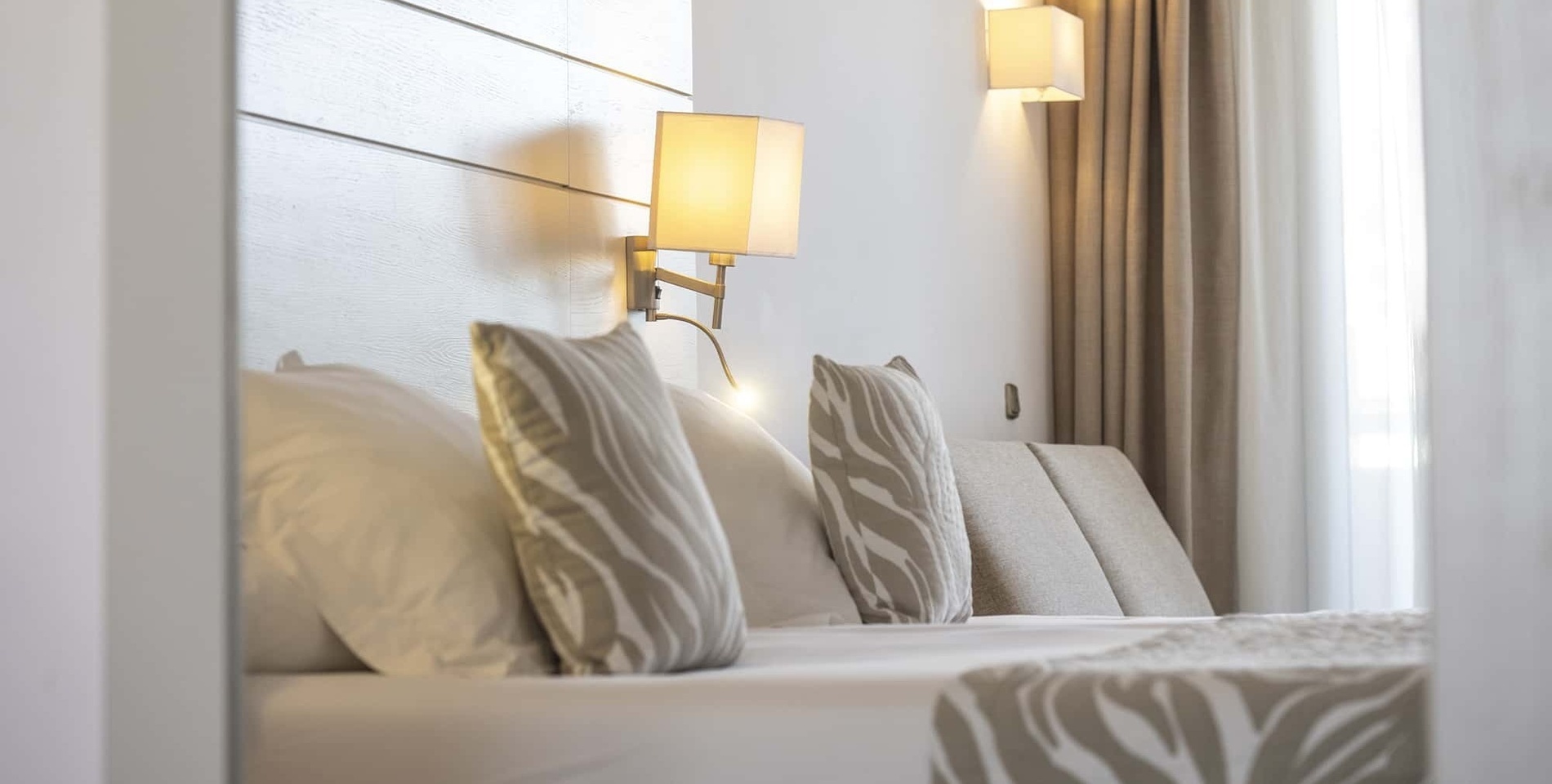 a hotel room with a bed and two lamps on the wall