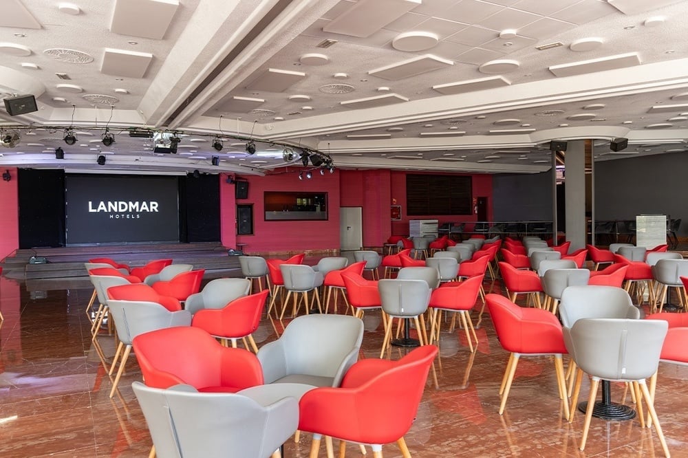 une grande salle avec des chaises rouges et blanches et un grand écran avec le logo landmar