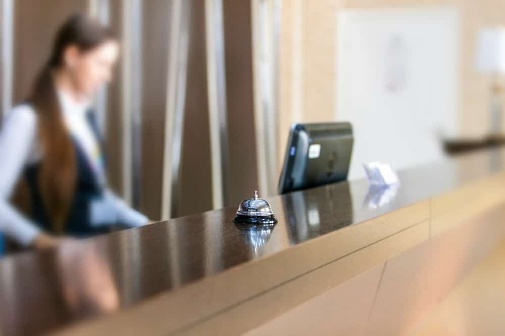 a woman is standing at a hotel reception desk .