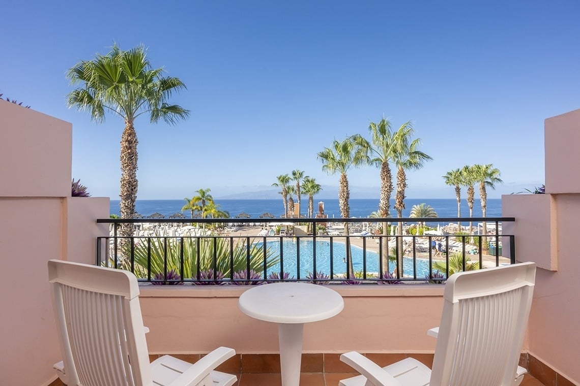 un balcon avec deux chaises et une table avec vue sur l' océan