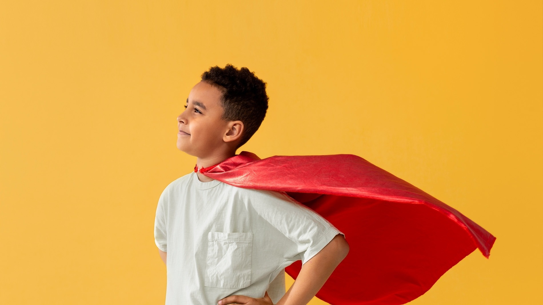 a young boy is wearing a red cape over his shoulders