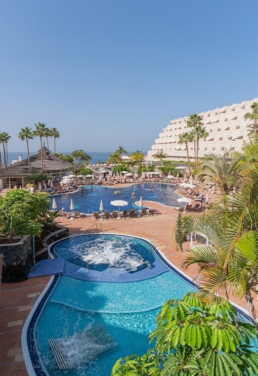 una gran piscina rodeada de sillas y sombrillas en un resort