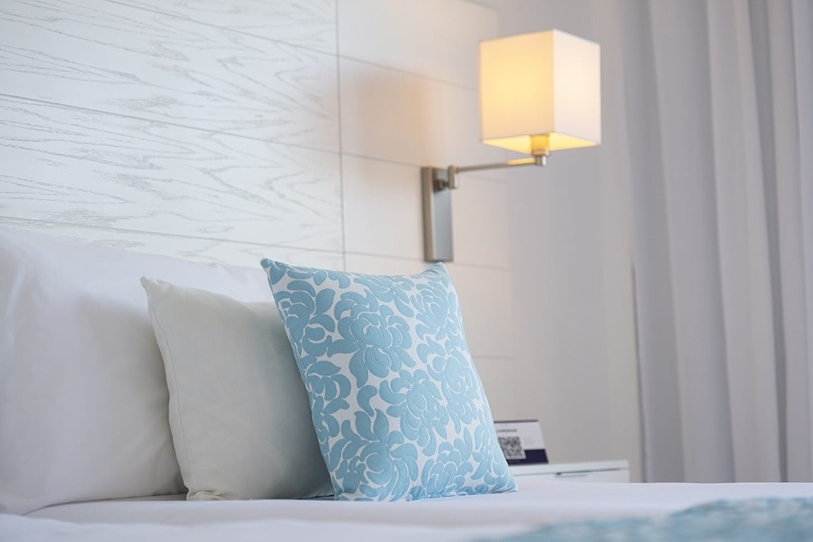 une chambre d' hôtel avec un lit blanc et un oreiller bleu