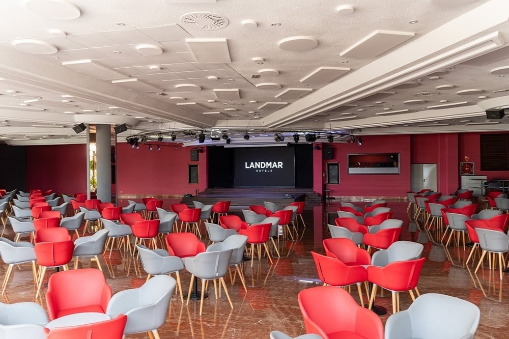 une salle de réunion avec des chaises rouges et blanches et un écran avec le logo landmar