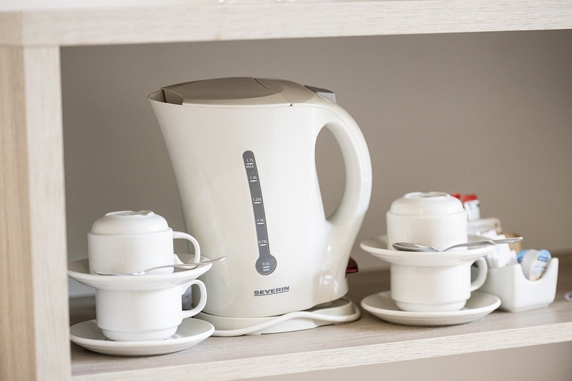 un bouilloire severin est sur une étagère avec des tasses et des cuillères