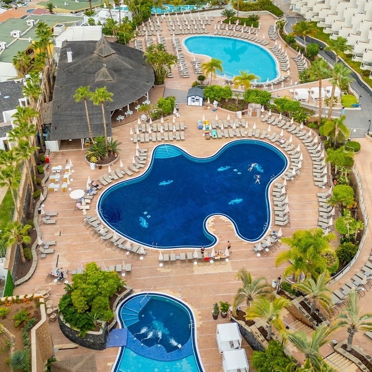 ein Hotel mit einem großen Pool und vielen Sonnenschirmen