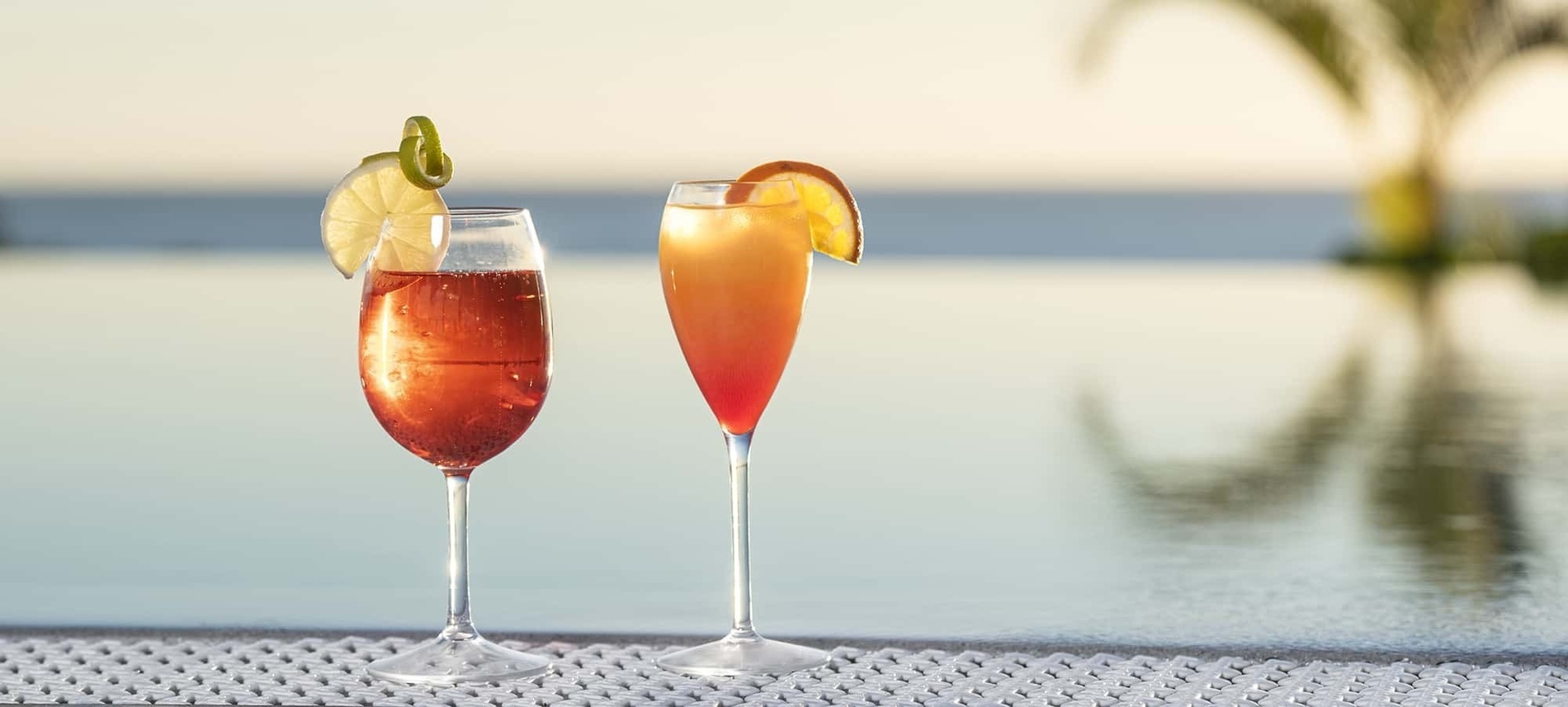 dos copas de vino están junto a una piscina