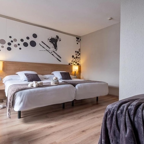 a hotel room with two beds and a painting of a skier on the wall