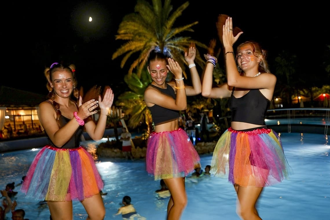 three girls wearing tutus are dancing in a pool