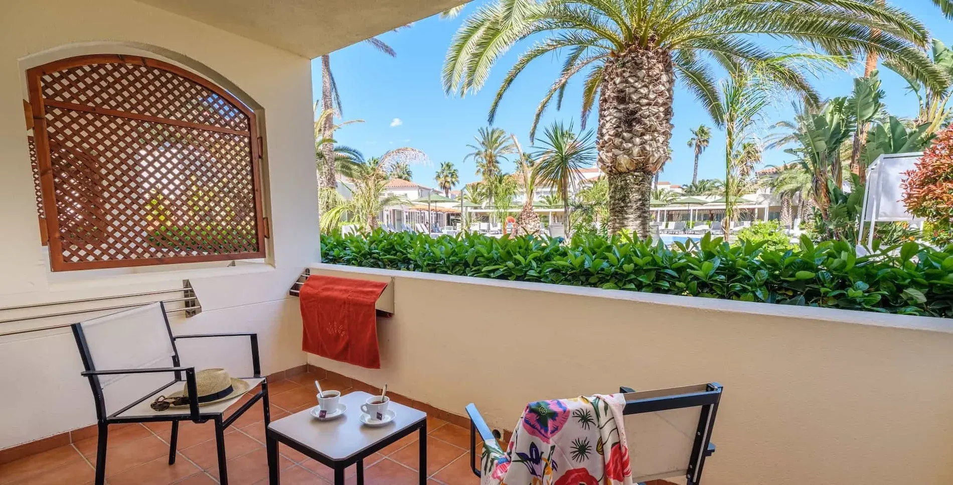 Gemütliches Zimmer mit Terrasse, Blick auf Pool & Palmen – Sommerurlaub in Tarragona. Buchen Sie auf der offiziellen Website.