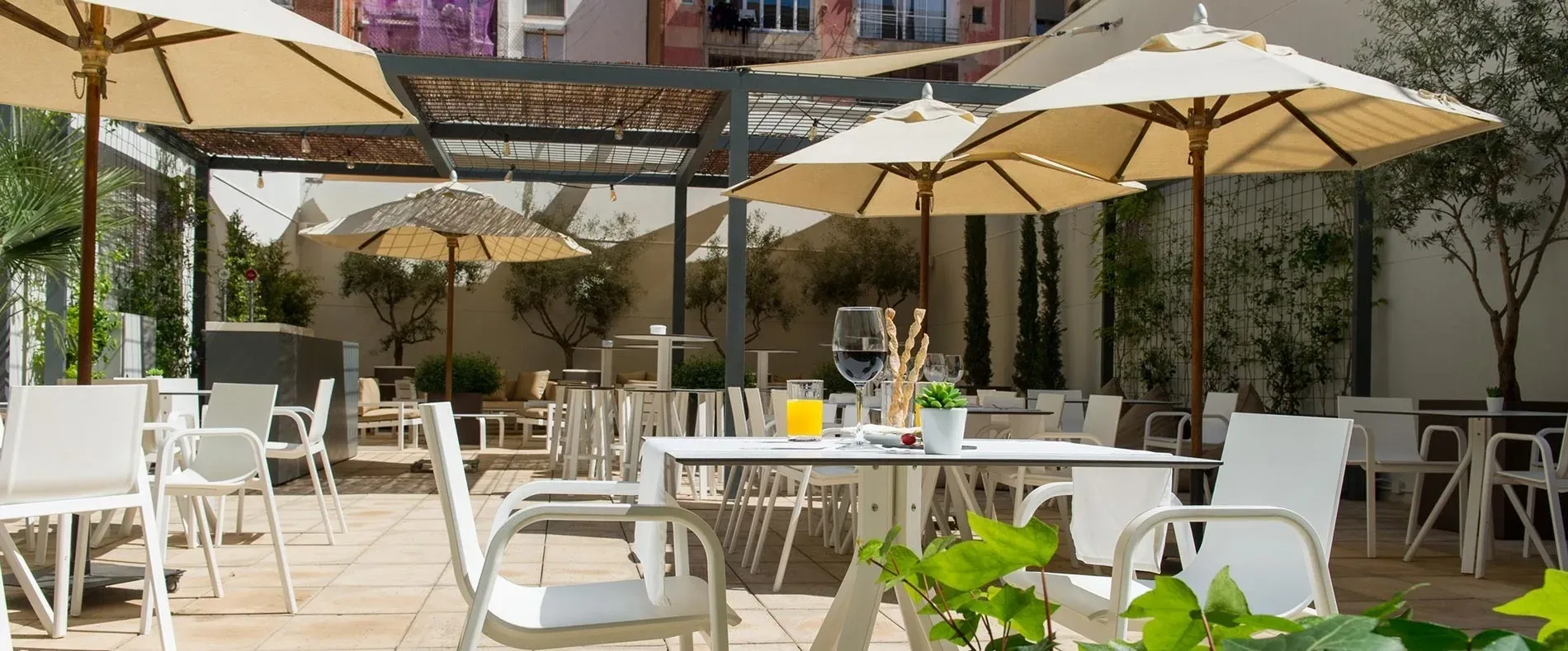 Entspannter Hotelgarten mit Tischen, Stühlen & Sonnenschirmen – Dienstleistungen | Estival Vilamari | Barcelona | Estival Group Hotels