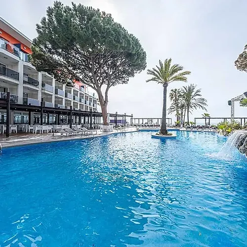 ESTIVAL: Crystal blue pool with waterfall and palm trees, resort hotel.