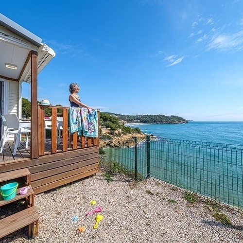a woman stands on the deck of a mobile home overlooking the ocean