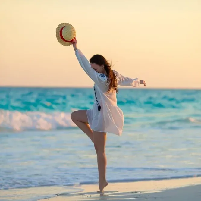 ESTIVAL: Corporativa - Mujer bailando en la playa al atardecer.