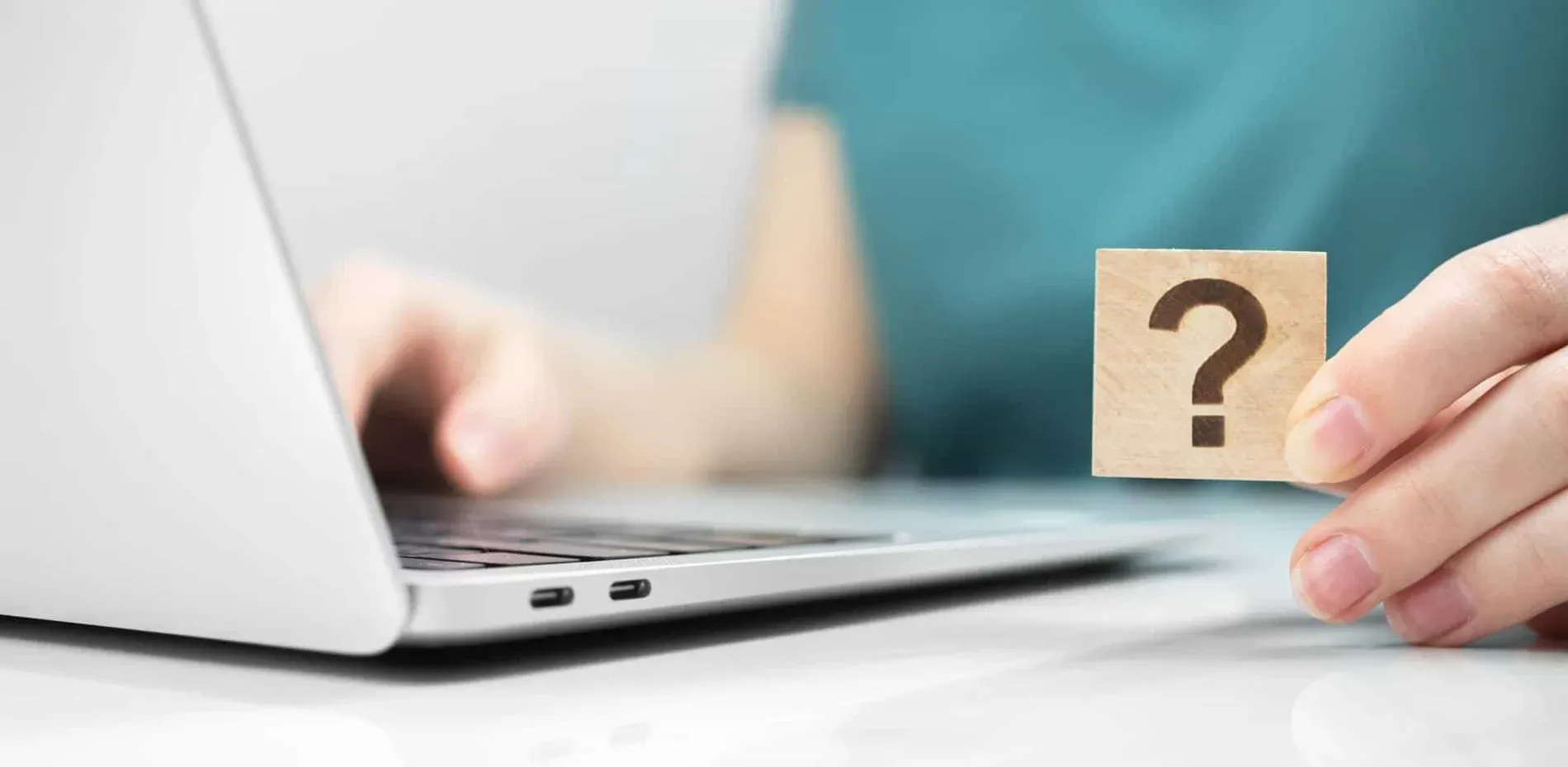 ESTIVAL: Firmenveranstaltungen - Person sucht Antworten mit Fragezeichenwürfel neben Laptop.
