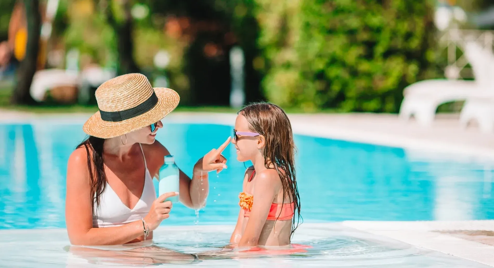 Mare i filla a la piscina, aplicant protecció solar. Ideal per al vostre hotel Tot Inclòs a Màlaga, Estival Group.
