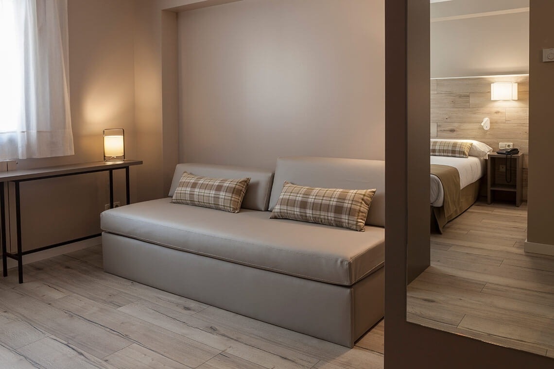 ESTIVAL: Corporativa: Sofá moderno y cama en suite con diseño minimalista.