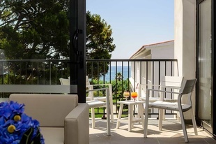 un balcón con una mesa y sillas y una bebida en la mesa