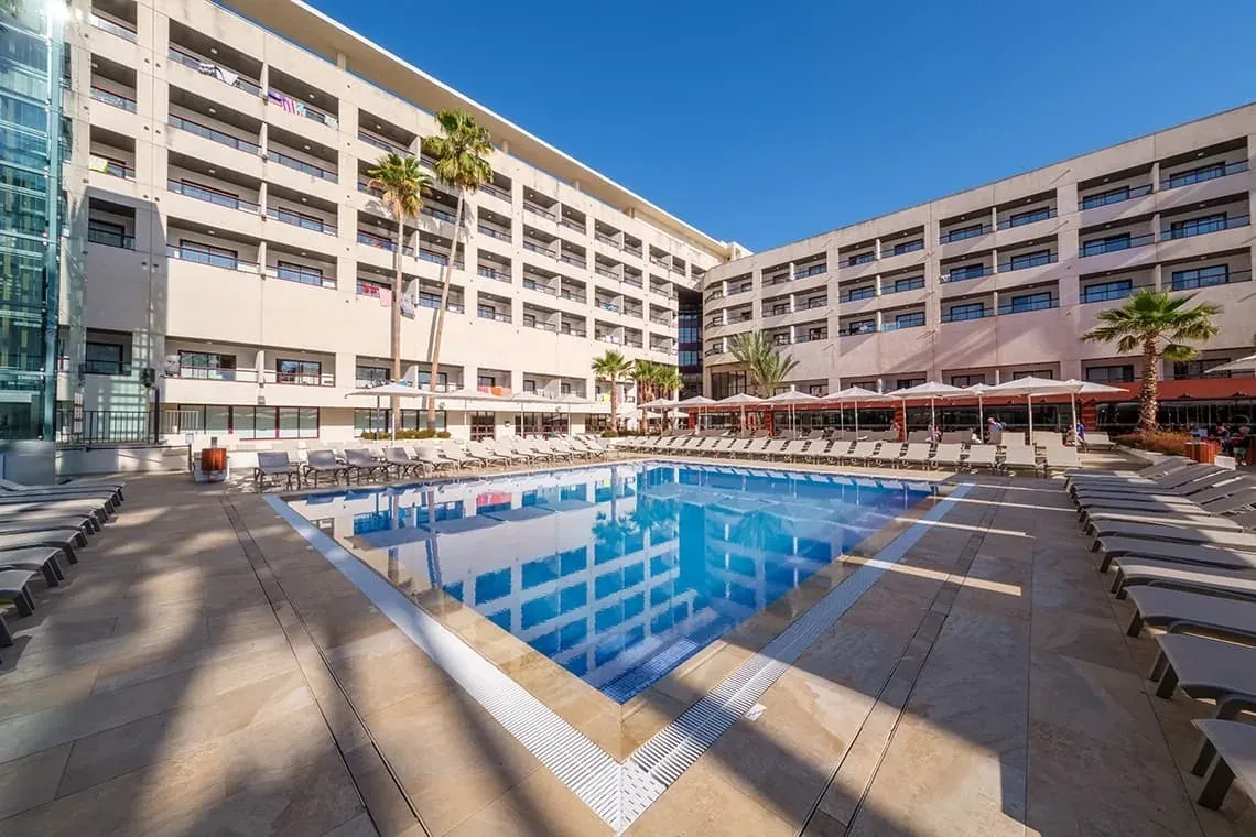 Piscina ESTIVAL: Corporativa con tumbonas y palmeras bajo sol brillante.