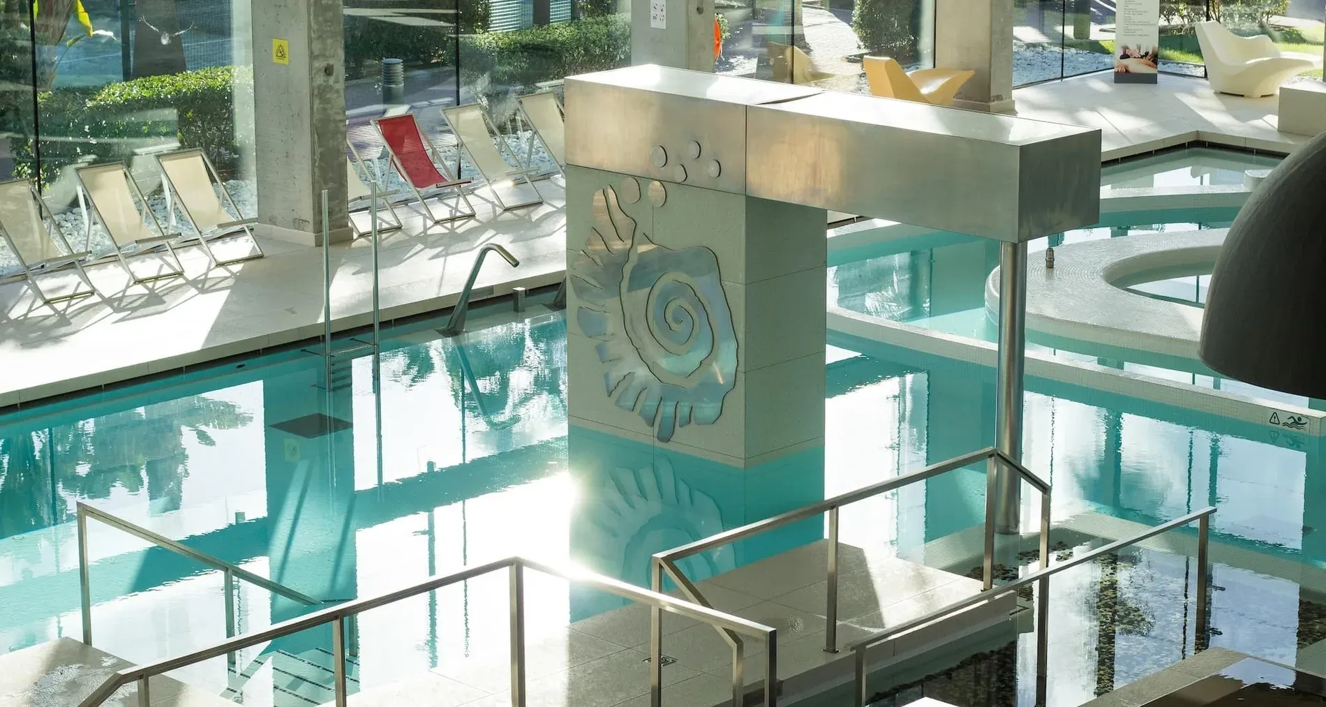 Indoor pool with lounge chairs and decorative column. Services | Estival Park Marena | La Pineda | Estival Group.