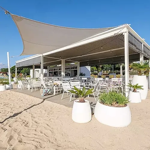 Estival Eldorado Resort: Restaurant a la platja amb taules i cadires blanques sota una carpa.