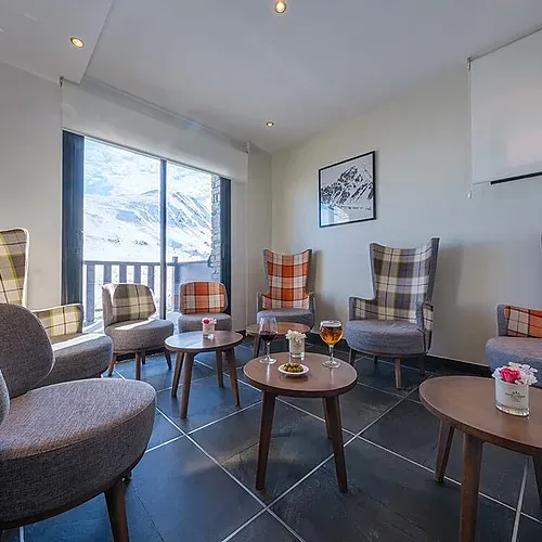 Salón acogedor de ESTIVAL: Corporativa con sillones de cuadros y vistas a la montaña.