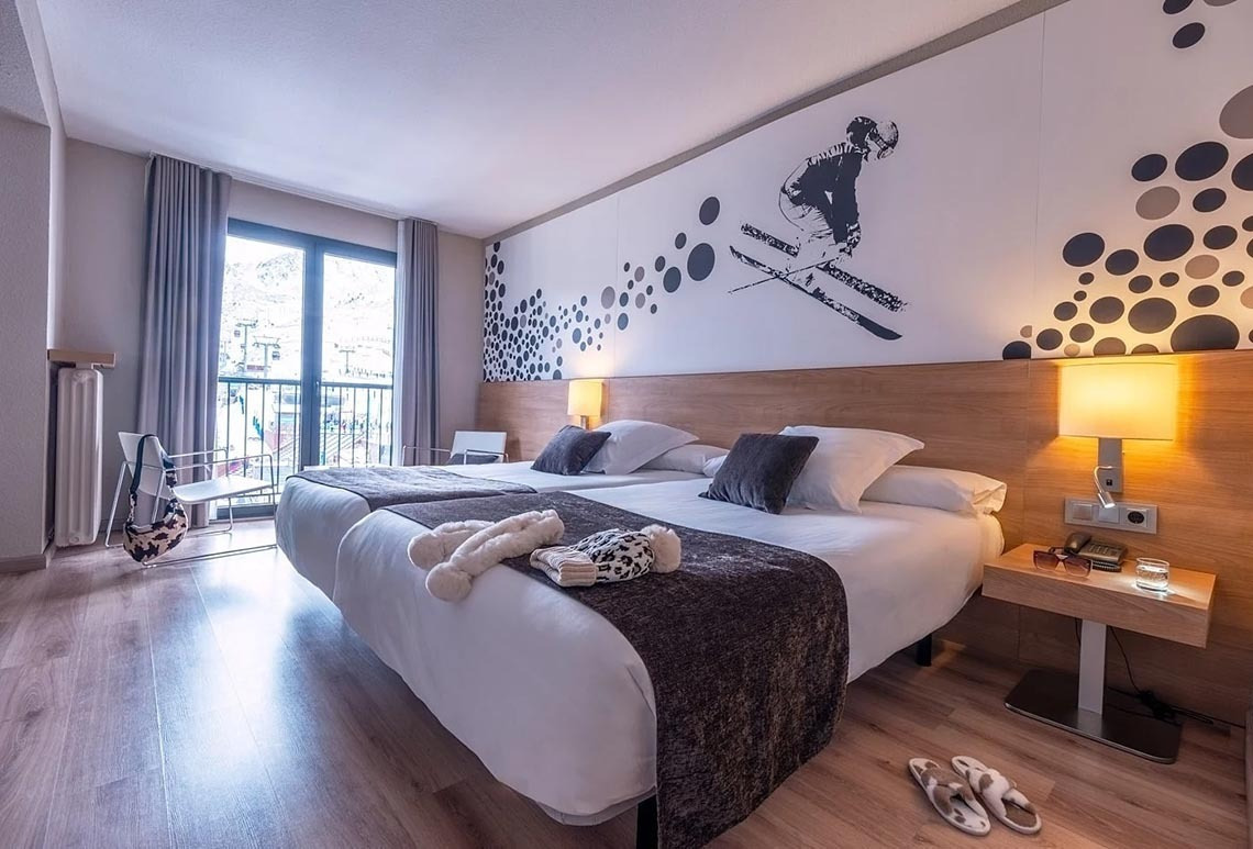 una habitació d' hotel amb dues camas i una imatge d' un esquiador a la paret