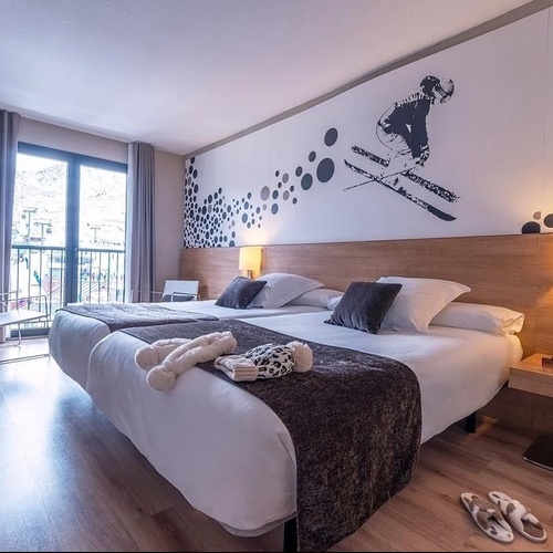 una habitació d' hotel amb dues camas i una imatge d' un esquiador a la paret