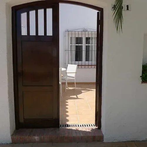Estival Eldorado Resort | Estival Group: Entrada amb porta de fusta fosca i jardí interior amb taula i cadires.