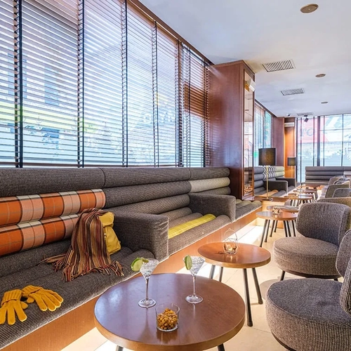 Hotel Sporting Andorra | Grandvalira: Stylish lounge with plaid cushions, drinks, and cozy chairs.