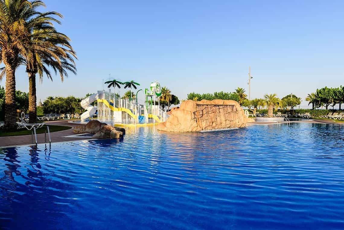 una piscina con toboganes y palmeras en el fondo