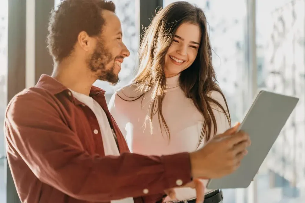 ESTIVAL: Corporativa - Pareja sonriente revisando tablet, ideal para eventos.