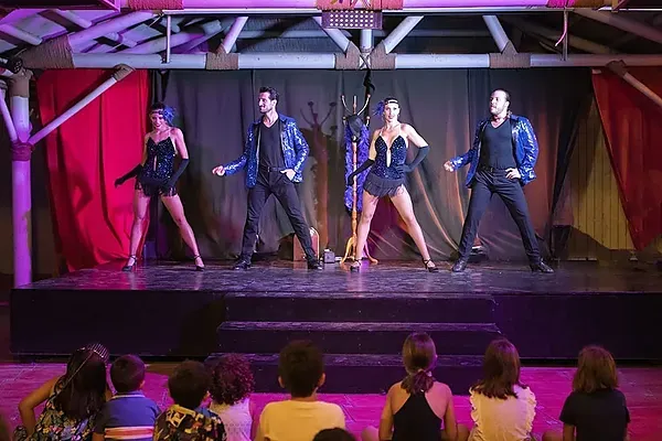 Actuación corporativa de ESTIVAL: Bailarines de cabaret en escenario con público infantil.