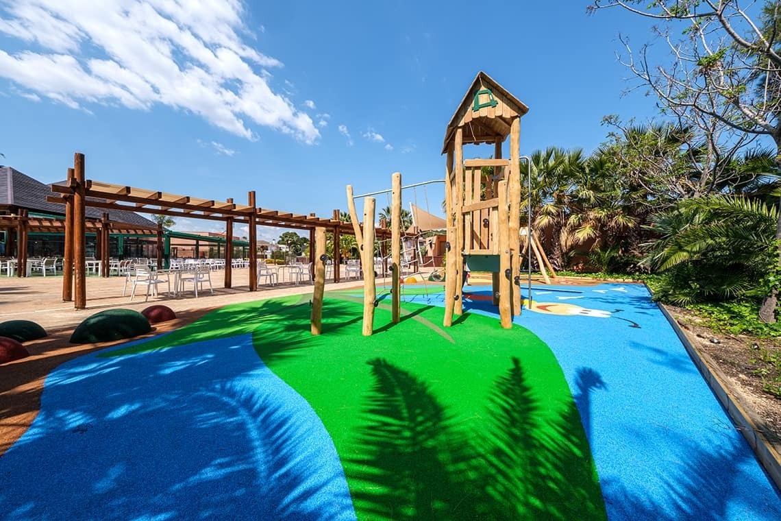 un parque infantil con una torre de madera y un columpio