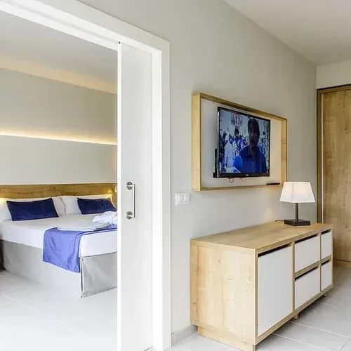 Habitació Estival Eldorado Resort: llit doble, TV, armari i vista al jardí. Estival Group.