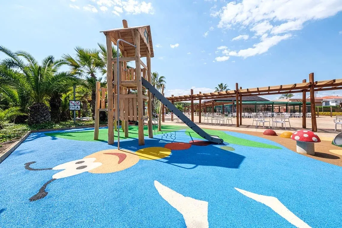 Parc infantil ESTIVAL: Corporativa amb tobogan, palmeres i zona de jocs.