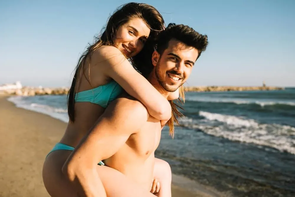 Smiling couple enjoying the beach, perfect for ESTIVAL: Corporate events.