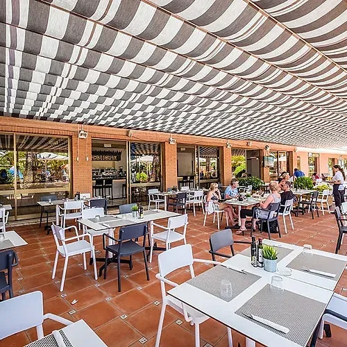 Terraza al aire libre del Estival Vendrell Platja con mesas y sillas listas para disfrutar del sol.
