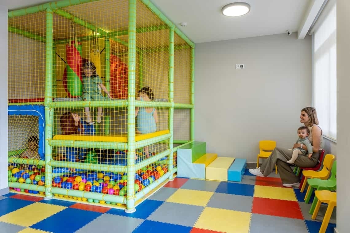 a woman is holding a baby in a play room