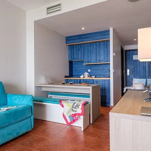 Bright hotel room with blue sofa & kitchen at Estival Islantilla 4* Huelva.