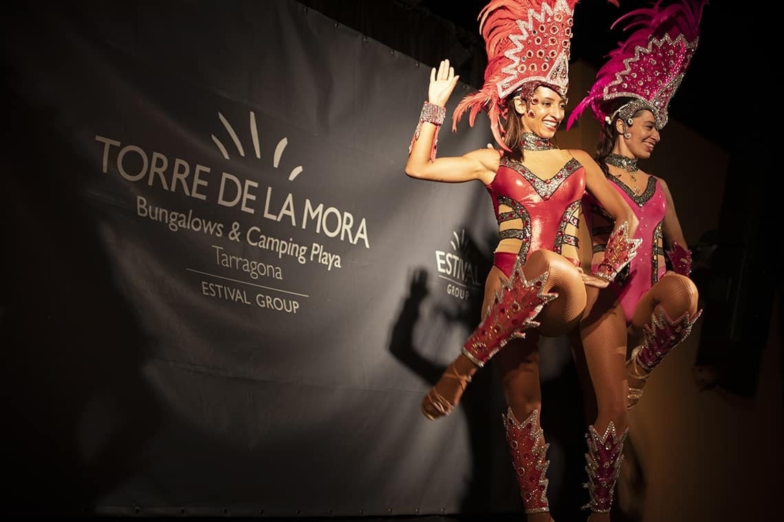 dos mujeres bailan frente a una pancarta que dice torre de la mora