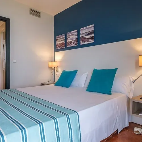 Bright hotel room at Estival Islantilla 4* with blue accents and a view of the bathroom.