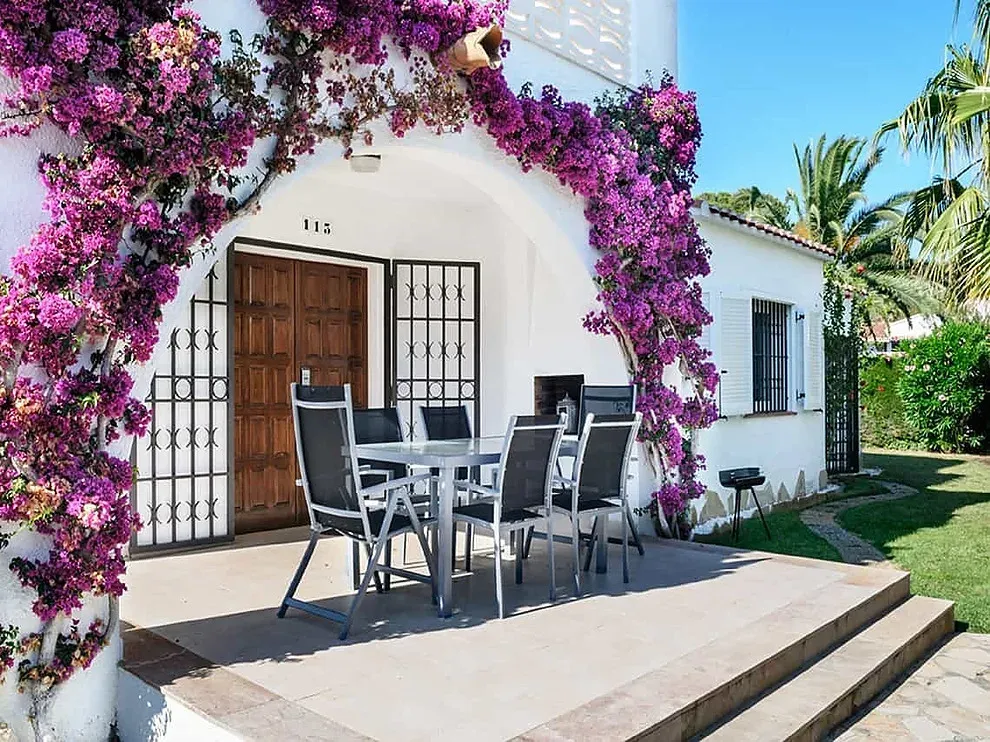 ESTIVAL: Patio con flores y mesa exterior.