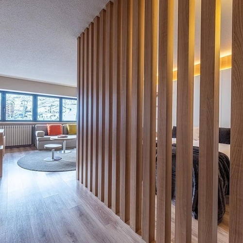 a hotel room with a wooden divider between the bedroom and the living room