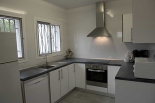 una cocina con gabinetes blancos y electrodomésticos de acero inoxidable