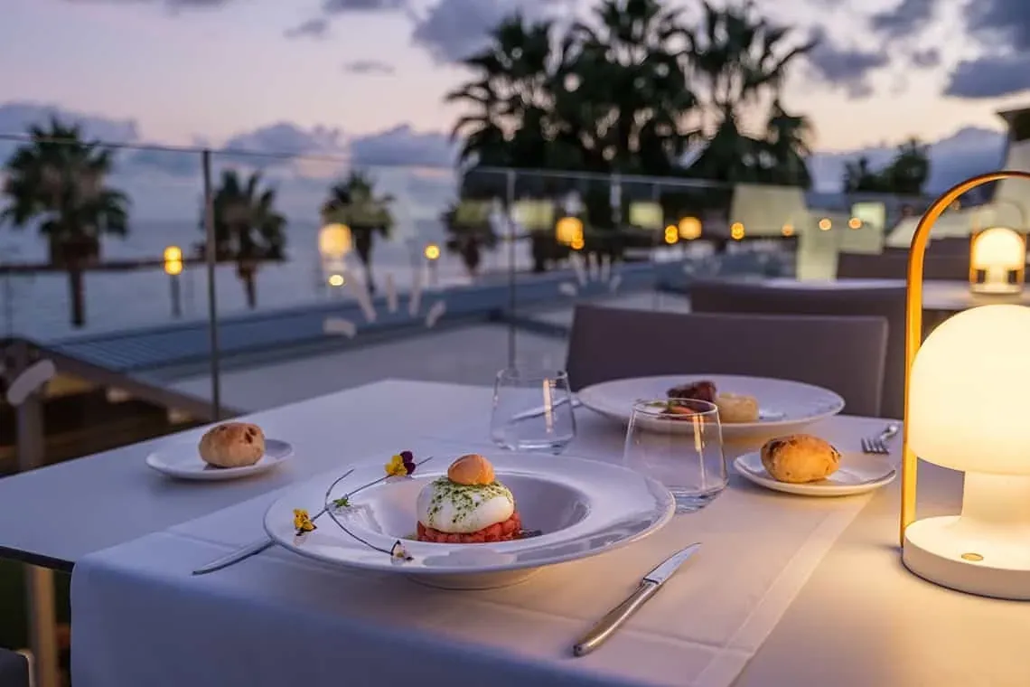 Cena romántica en ESTIVAL: Corporativa, mesa con vistas al mar al atardecer.